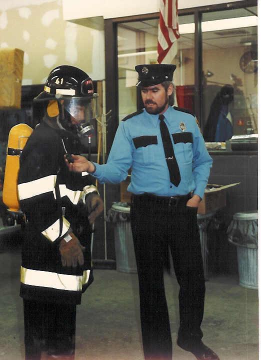 Mark Backus in uniform with individual in old time bunker gear